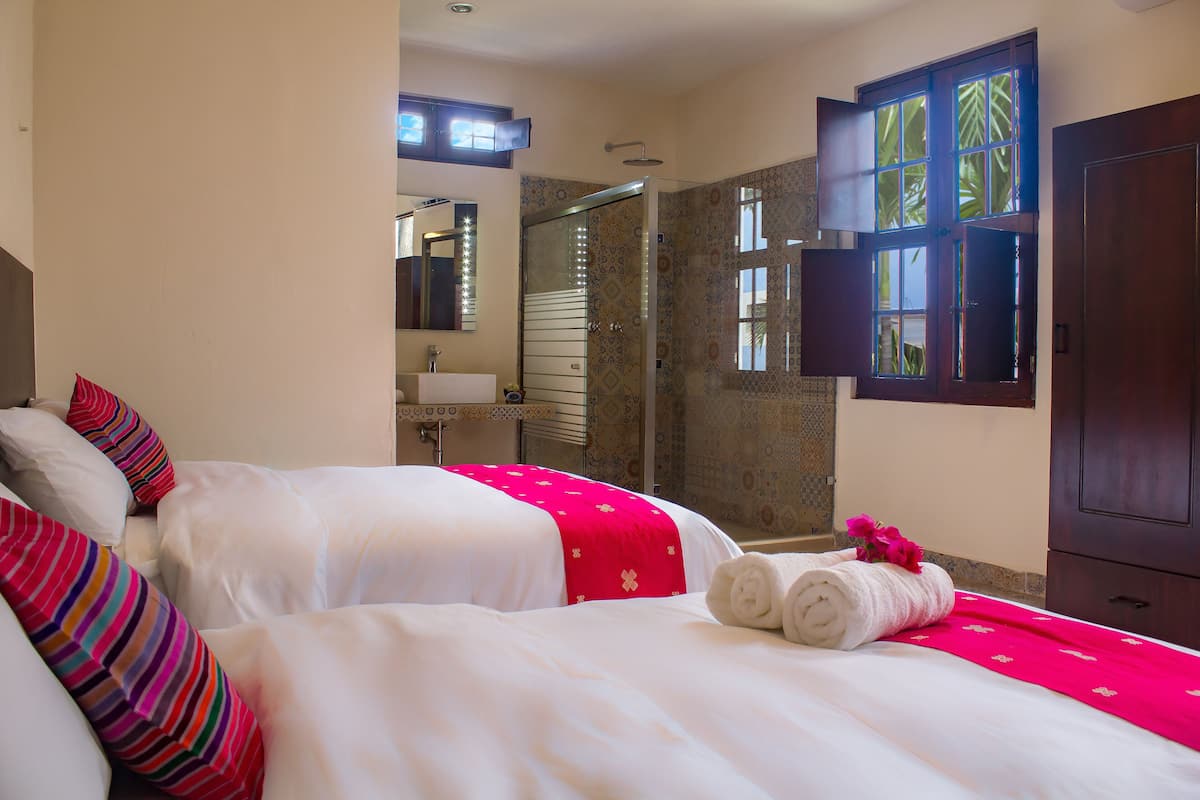 Una camera d'albergo con due letti, un bagno e una zona doccia.