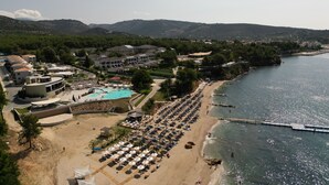 Une station balnéaire dotée d’une piscine, de parasols de plage et offrant une vue sur la mer.