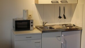 Une cuisine de taille réduite équipée d’un four à micro-ondes, d’un évier et de placards.