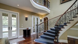 Una imponente escalera con barandales negros ornamentados y peldaños de madera que conducen a un nivel superior.