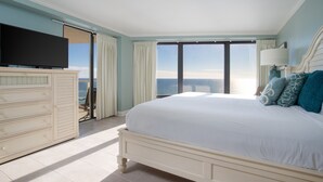 Un dormitorio con una cama grande, un televisor en una cómoda y vista al océano.