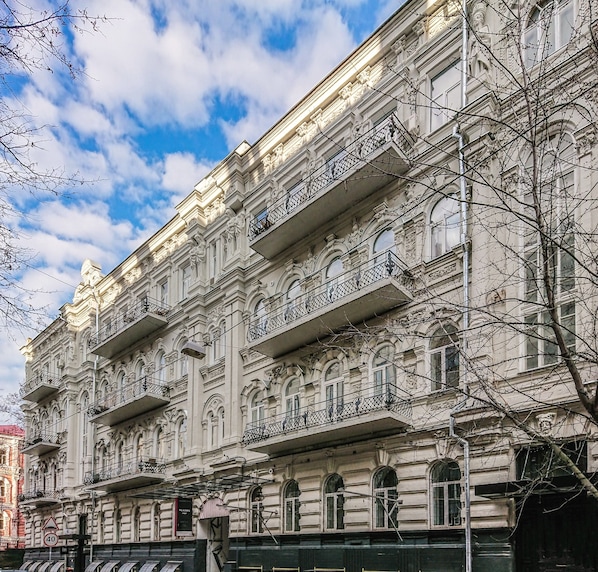 Un edificio histórico con detalles arquitectónicos ornamentales, varios balcones y una fachada clásica.