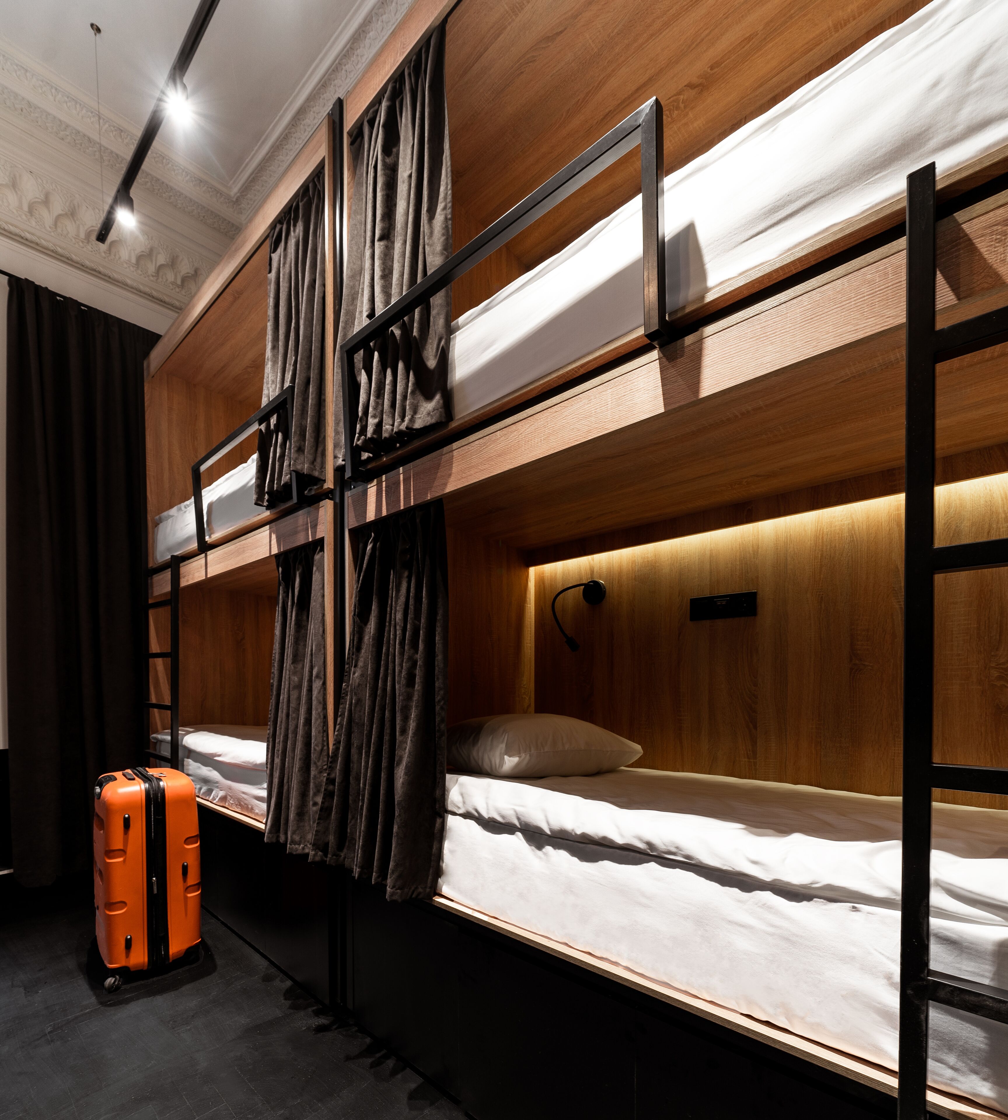 Dormitorio con literas, una maleta, paredes de madera y una lámpara en el techo.