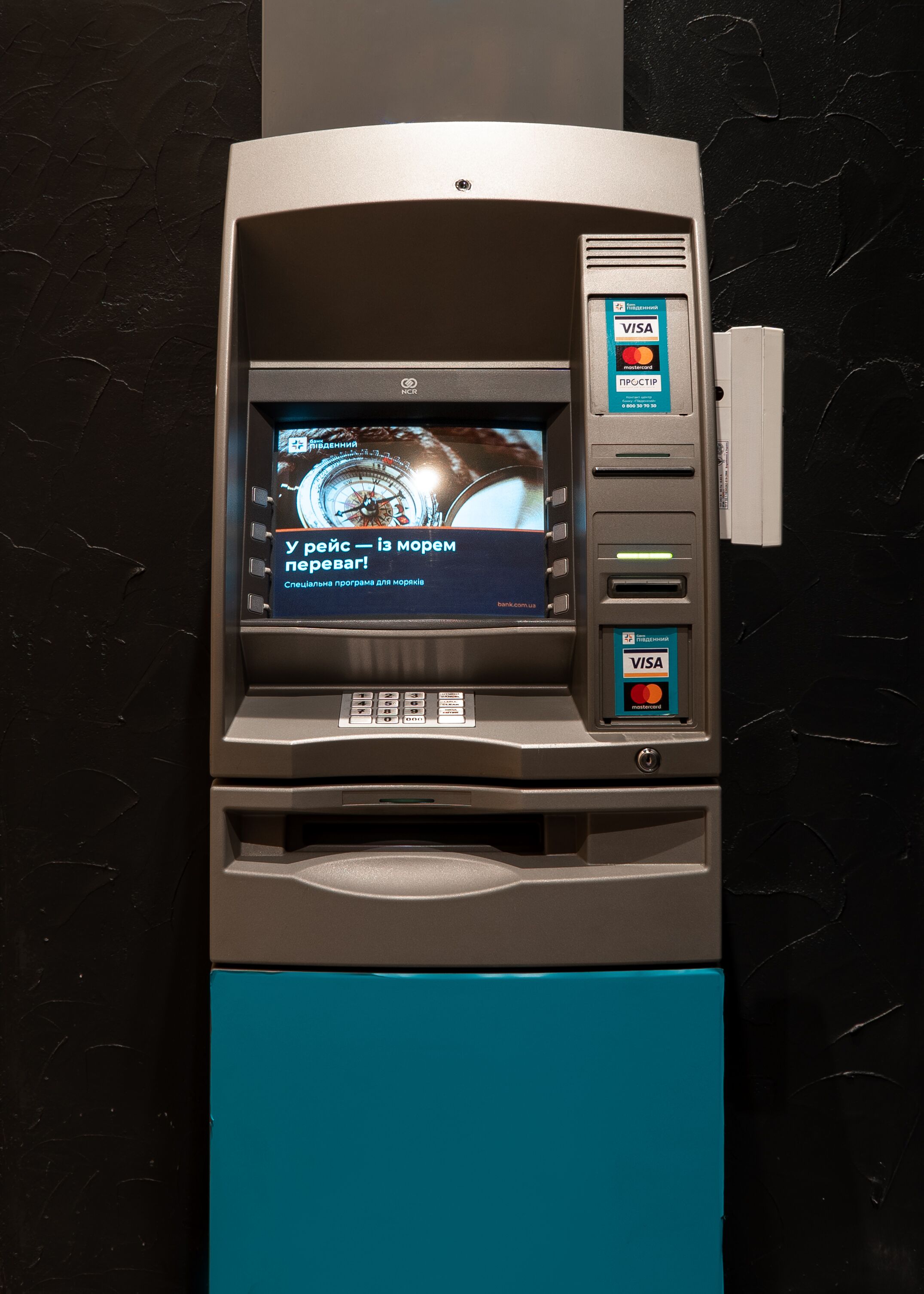 An ATM with a screen displaying a watch advertisement and a message in a foreign language.