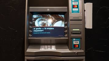 An ATM with a screen displaying a watch advertisement and a message in a foreign language.