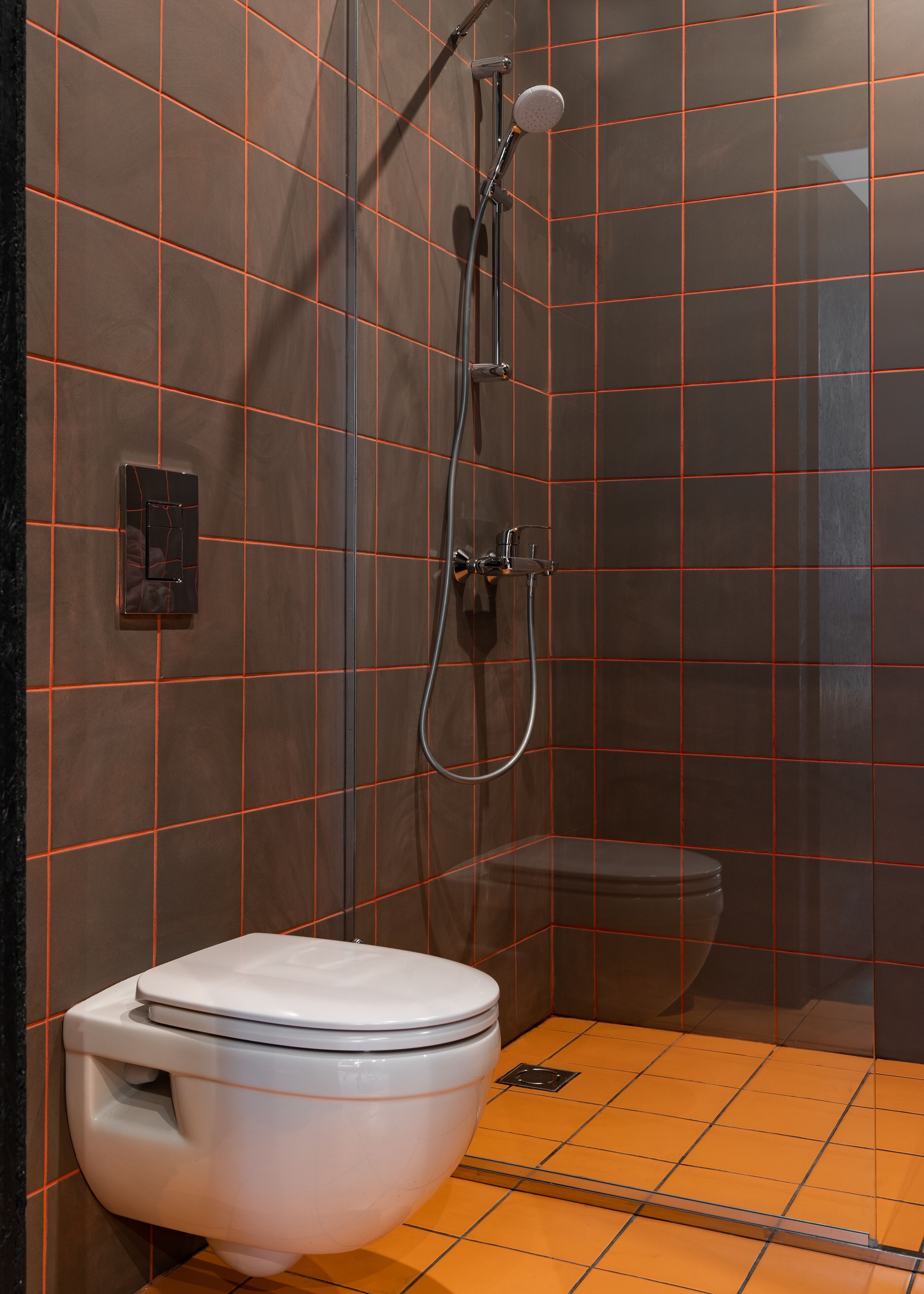 A modern bathroom with a shower, toilet, and a control panel on the wall.