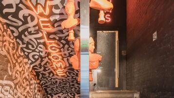 A staircase leading to a cafe reception with graffiti on the walls and a neon sign.