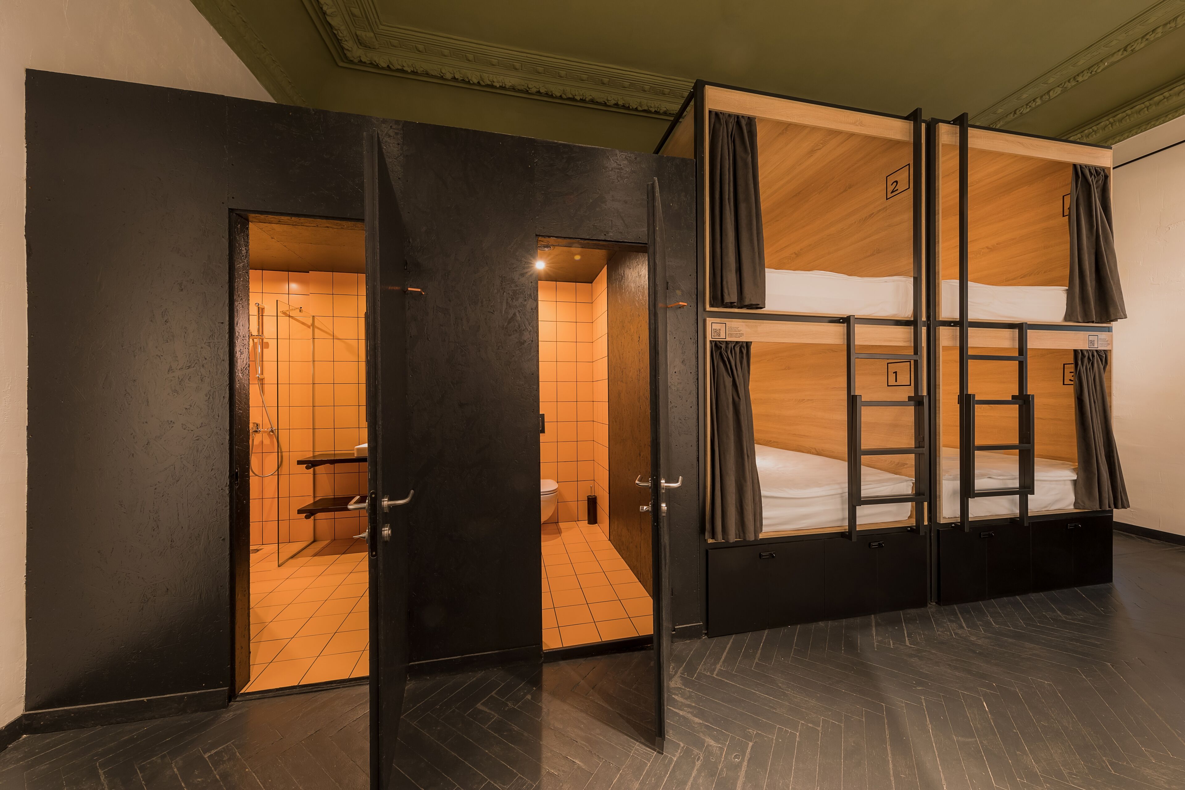 Ein Zimmer mit Etagenbetten, einem Badezimmer mit Dusche und einer Tür zu einem weiteren Zimmer.