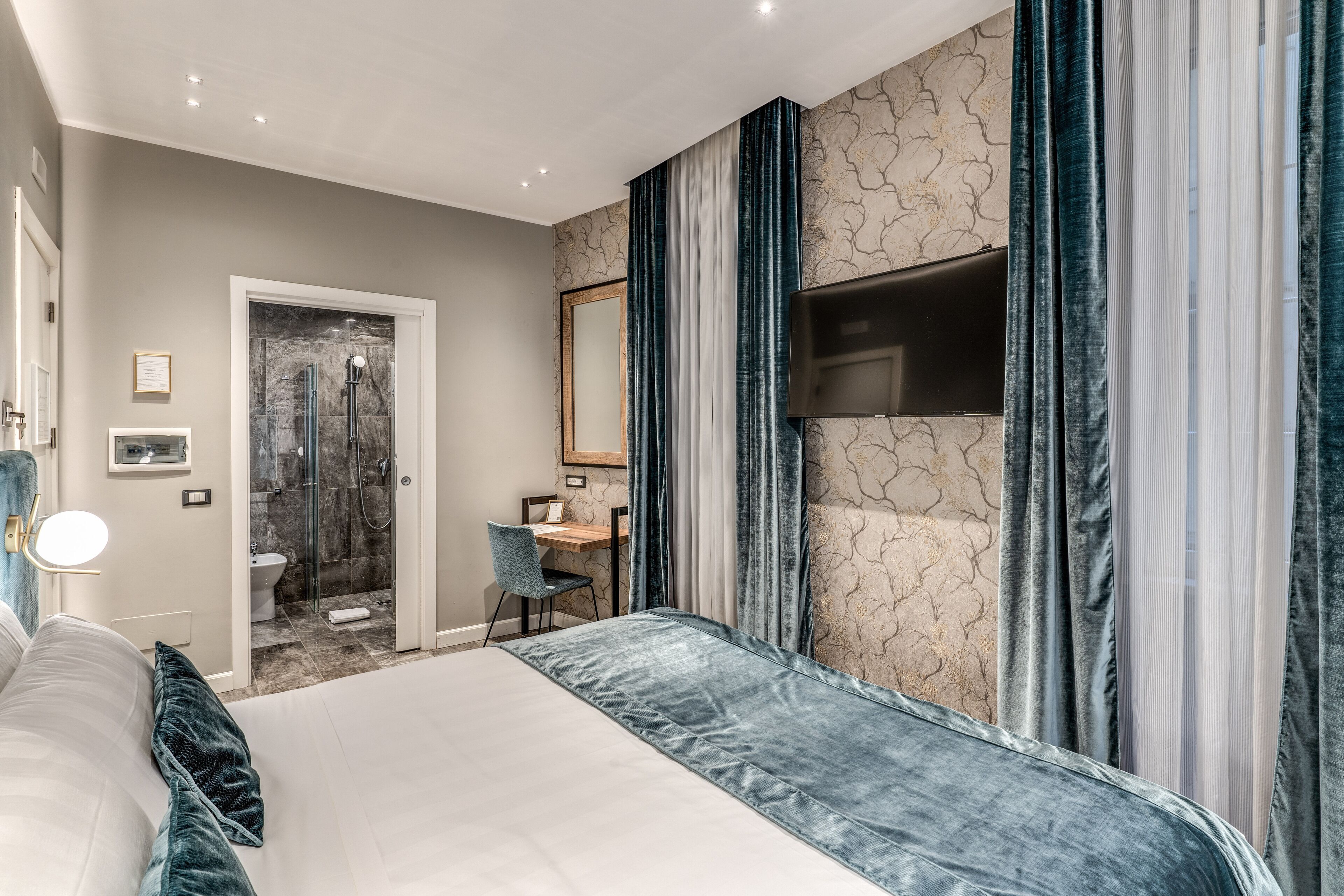 A modern hotel room with a large bed, a desk, and a shower area.