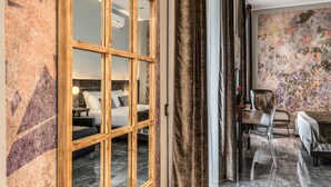 Et hotelværelse med stort vindue, seng, skrivebord og stol.