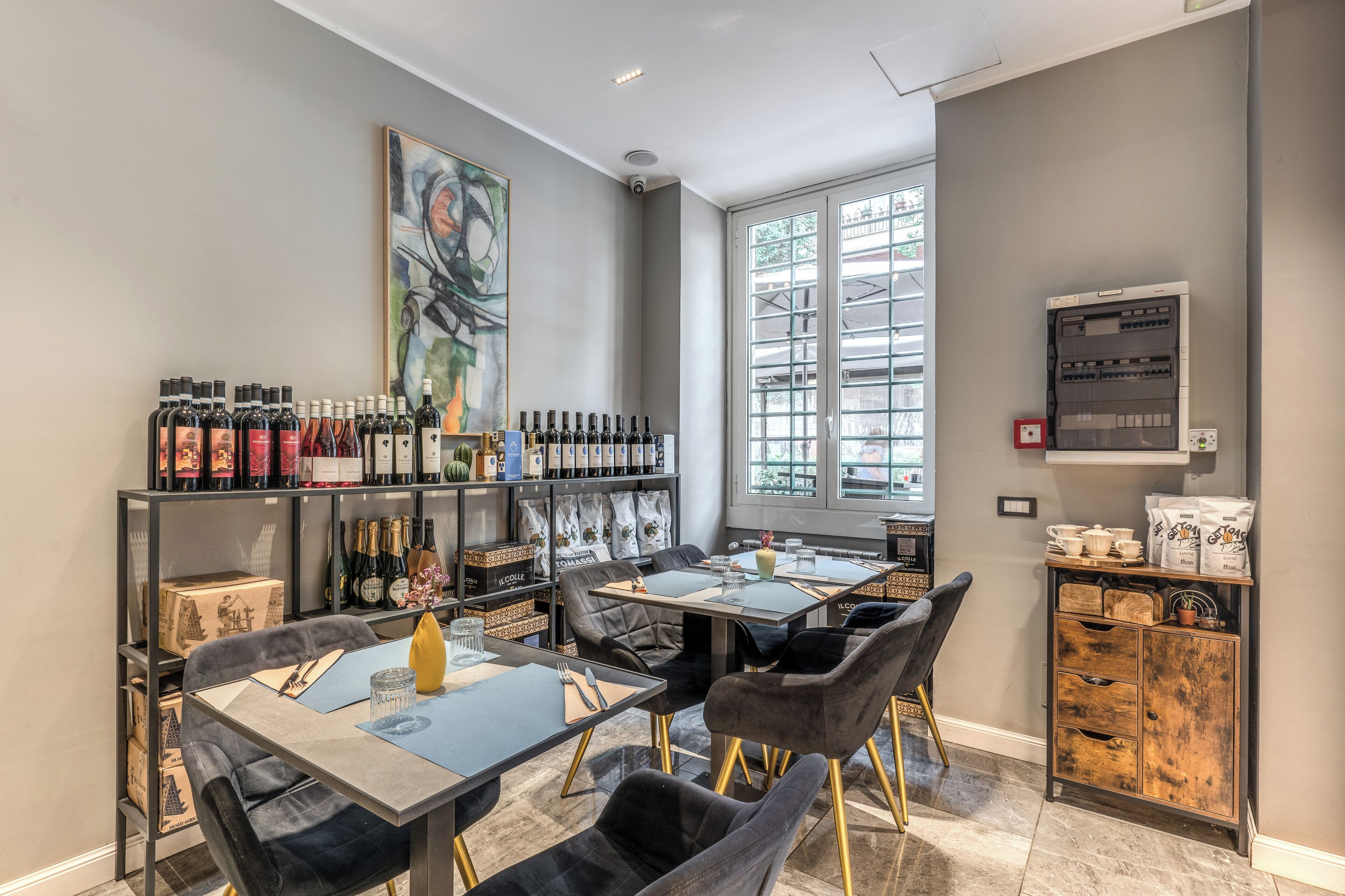 Un espace repas moderne avec des tables et des chaises, un meuble à vin et une grande fenêtre.