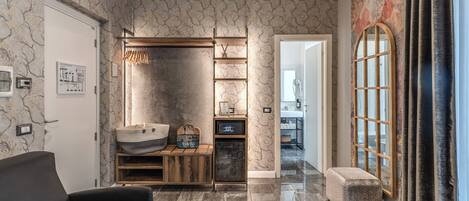 A modern living room with a sofa, built-in shelving, a small refrigerator, and a decorative wall.