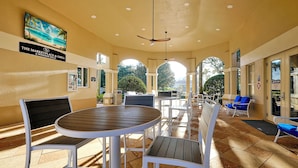 A covered outdoor seating area with tables and chairs, a ceiling fan, and a view of the outdoors. - Minutes Away from Theme Parks! 3-Bed Townhome, 6 minutes to Disney World! (Kissimmee)
