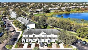 A residential area with a large white house featuring a central driveway and multiple cars parked. - Minutes Away from Theme Parks! 3-Bed Townhome, 6 minutes to Disney World! (Kissimmee)