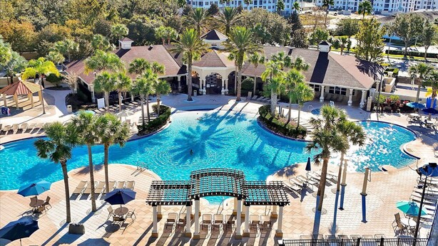 A resort with a large central pool, multiple lounge areas, and a building with a tiled roof. - Minutes Away from Theme Parks! 3-Bed Townhome, 6 minutes to Disney World! (Kissimmee)