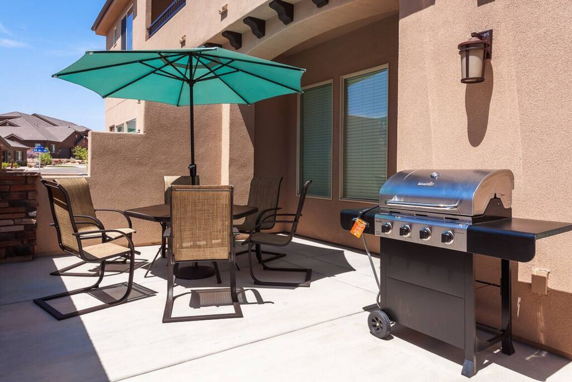 Une terrasse extérieure équipée d’un barbecue, de chaises et d’un parasol.