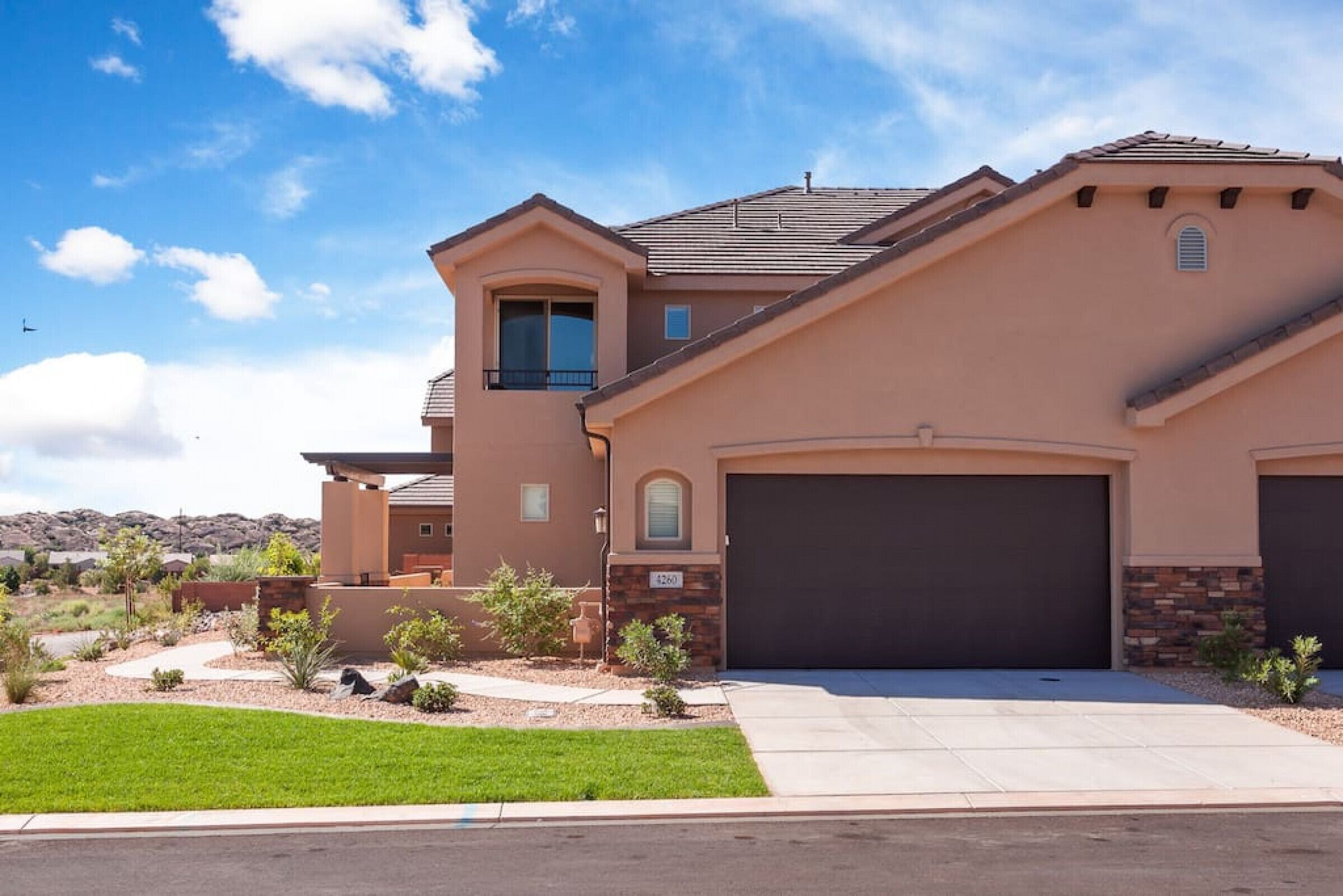 A modern two-story house with a garage, a small balcony, and a well-maintained lawn.