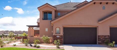A modern two-story house with a garage, a small balcony, and a well-maintained lawn.
