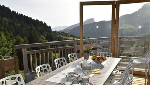 A wooden deck with a table set for tea, surrounded by white chairs, overlooking a mountainous landscape. - Luxury Chalet with Ski-In/Ski-Out, Sauna & Outdoor Jacuzzi at Le Grand-Bornand (Le Grand-Bornand)