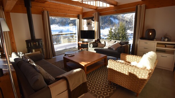 A cozy living room with a fireplace, sofa, and television, overlooking a snowy landscape. - Luxury Chalet with Ski-In/Ski-Out, Sauna & Outdoor Jacuzzi at Le Grand-Bornand (Le Grand-Bornand)