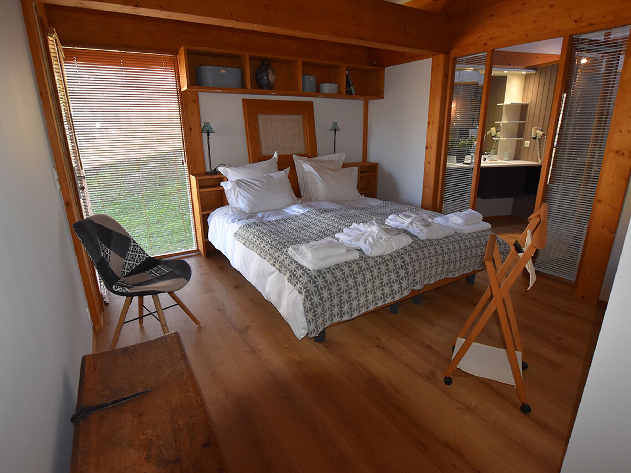 Een slaapkamer met een bed, een stoel, een bureau en een inbouwkast.