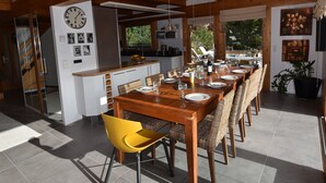 A spacious dining area with a wooden table set for a meal, surrounded by wicker chairs. - Luxury Chalet with Ski-In/Ski-Out, Sauna & Outdoor Jacuzzi at Le Grand-Bornand (Le Grand-Bornand)