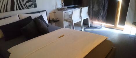 A hotel room with a bed, a desk, a television, and a chair.