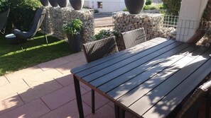Une terrasse extérieure avec une table et des chaises en bois, entourée de murs en pierre et de plantes en pot.
