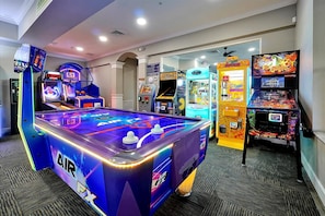A room with a foosball table, arcade games, and a pool table.