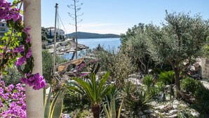 Ein Garten mit einer Pergola, verschiedenen Pflanzen und Blick aufs Meer.