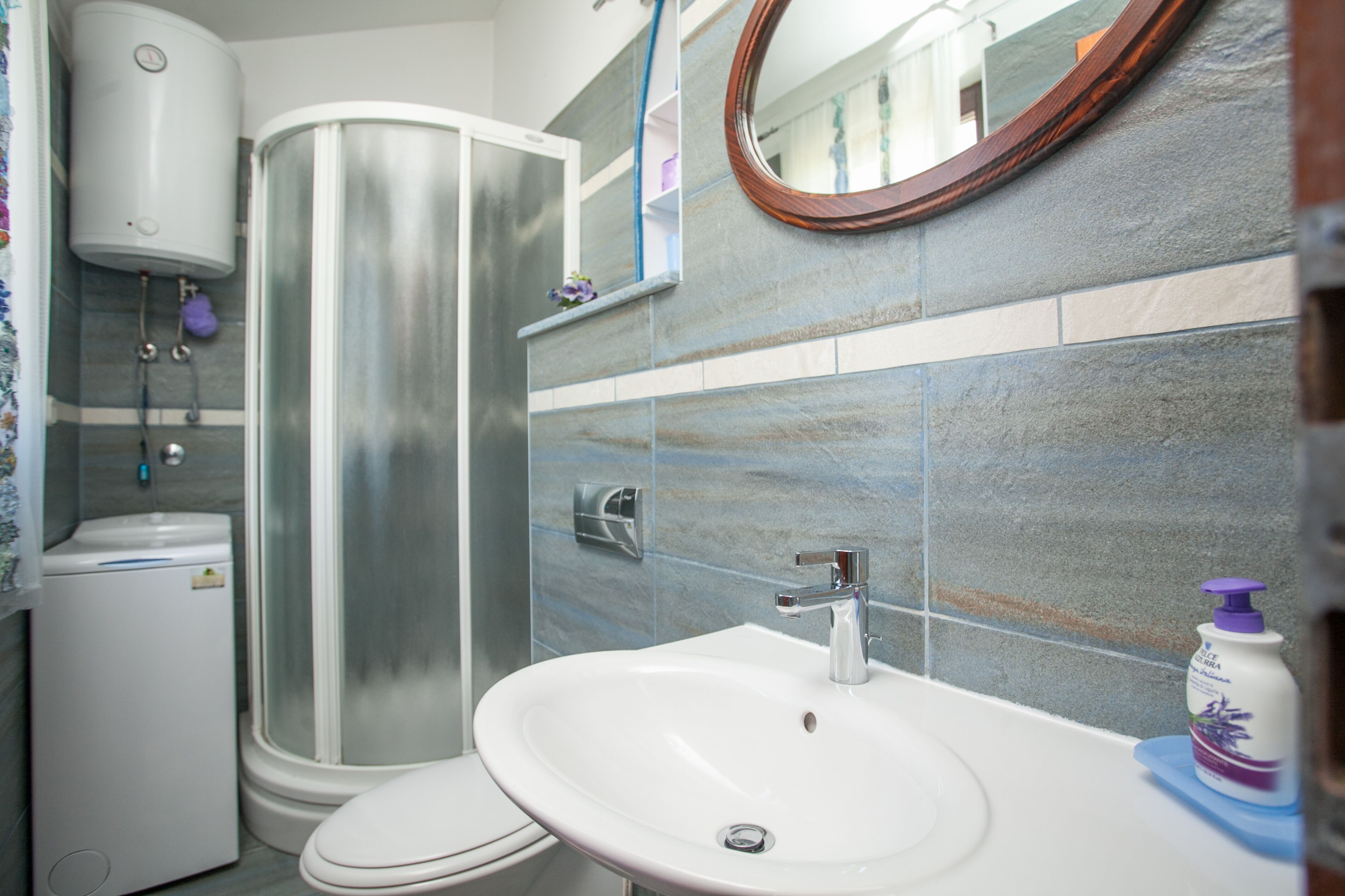 A bathroom with a shower, toilet, sink, and a mirror.