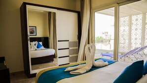 A hotel room with a bed, a wardrobe, and a balcony with sun loungers. - Three-Bedroom Apartment Serenity Home Hurghada 03 (Hurghada)
