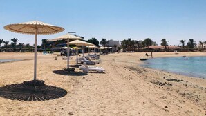 A beach with umbrellas, lounge chairs, and a clear sky. - Three-Bedroom Apartment Serenity Home Hurghada 03 (Hurghada)