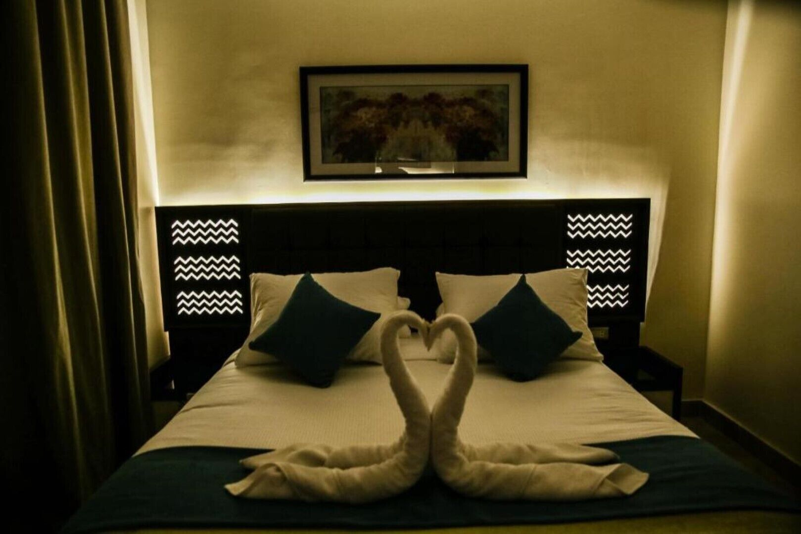 A bed with a heart-shaped arrangement of towels and pillows.