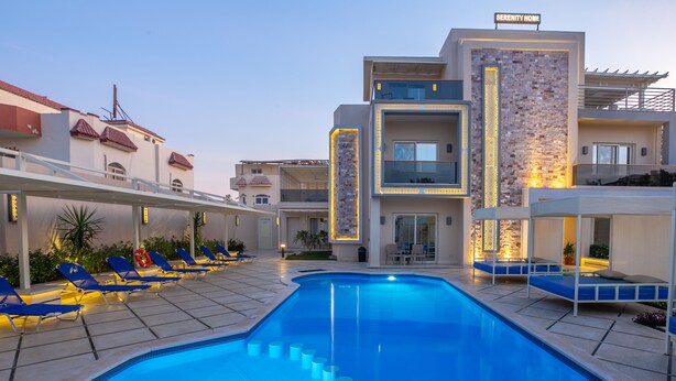 A modern hotel with a swimming pool, sun loungers, and a well-lit exterior. - Three-Bedroom Apartment Serenity Home Hurghada 03 (Hurghada)