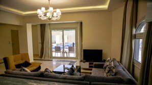 A living room with a sofa set, a flat-screen TV, and a chandelier. - Three-Bedroom Apartment Serenity Home Hurghada 03 (Hurghada)