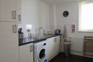 Een moderne keuken met een inbouw wasmachine, een spoelbak en een klok aan de muur.