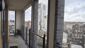 Un balcone con vista sugli edifici circostanti, un tavolo e delle sedie.