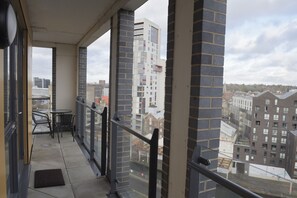 Een balkon met uitzicht op omliggende gebouwen, een tafel en stoelen.