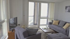 Un soggiorno moderno con un divano grigio, un tavolino da caffè e una TV a schermo piatto su un mobile in legno.