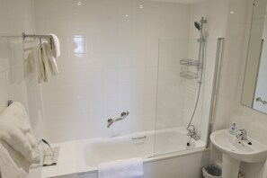 Een moderne badkamer met een badkuip, douche en wastafel.