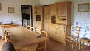 A dining area with a long wooden table and chairs, wooden cabinets, and a hanging light fixture. - Spacious Savoyard chalet apt, equipped kitchen, 4 bedrooms, 2 baths, Le Chinaillon (Le Grand-Bornand)