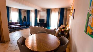 Un vaste espace de vie comprenant une table ronde en bois, des sièges confortables, un téléviseur à écran plat et un canapé.