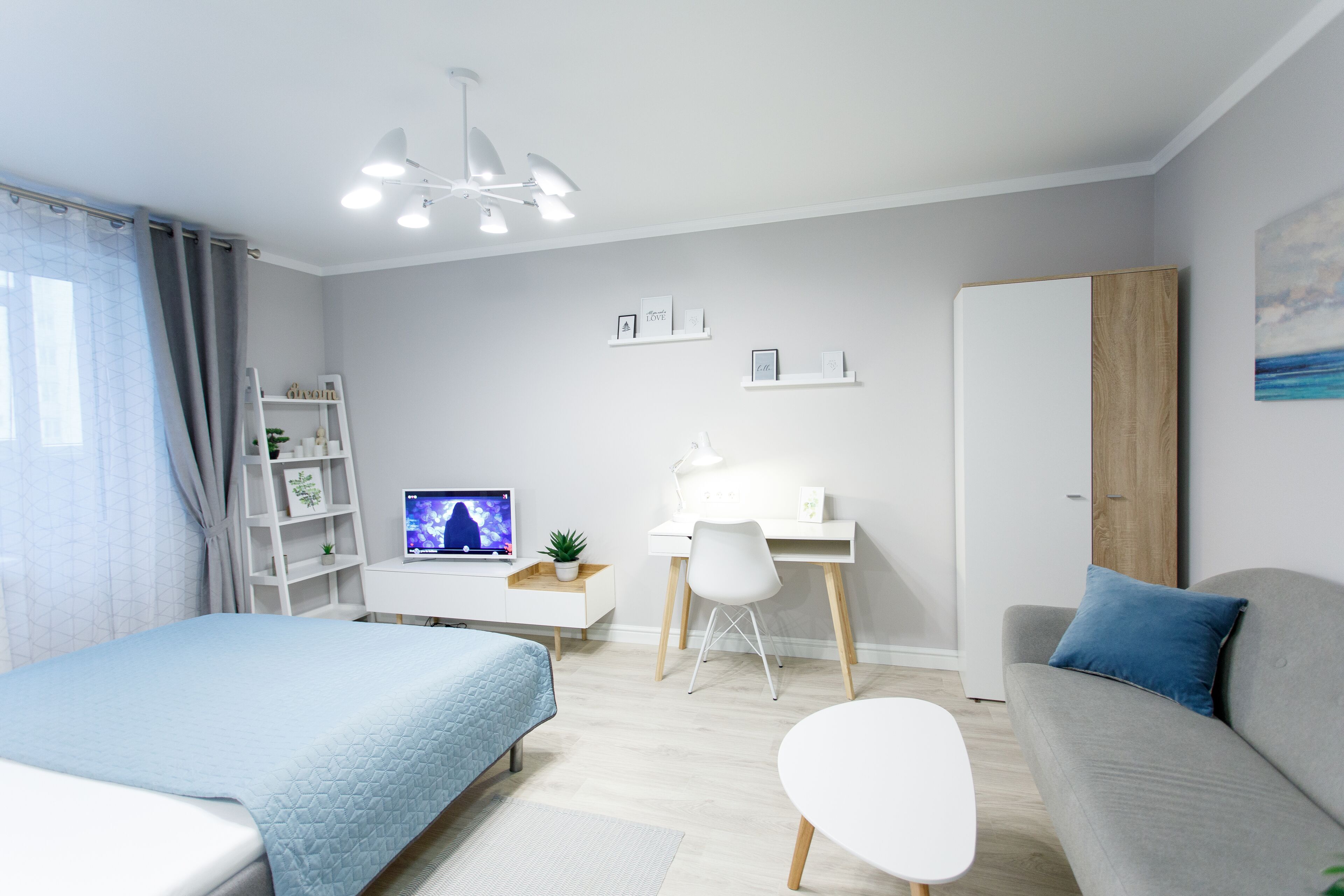 A modern bedroom with a bed, desk, and a grey sofa.