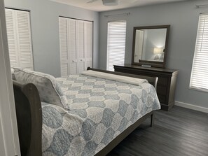 A bedroom with a bed, a dresser, a mirror, and a window with blinds. - 3BD/3BA w/Electric Dock/Heated Pool; SUMMER VACA; Gulf Access – BUDGET FRIENDLY! (Cape Coral)