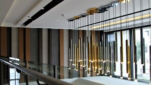 Un intérieur moderne avec une balustrade en verre, une rangée de luminaires verticaux et une vue dégagée grâce à de grandes fenêtres.