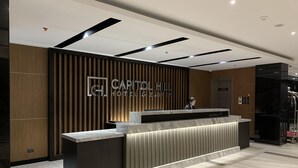 Un comptoir d’accueil d’hôtel au design moderne, comprenant un espace d’accueil, un panneau mural et un comptoir de réception.