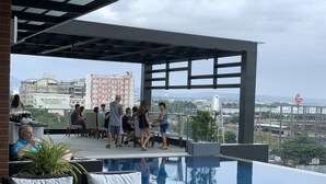Un espace piscine extérieur avec des chaises longues et une vue sur le paysage urbain.