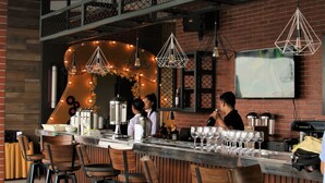 Un espace bar doté d’un long comptoir, de nombreux tabourets et d’un mur en briques en arrière-plan.
