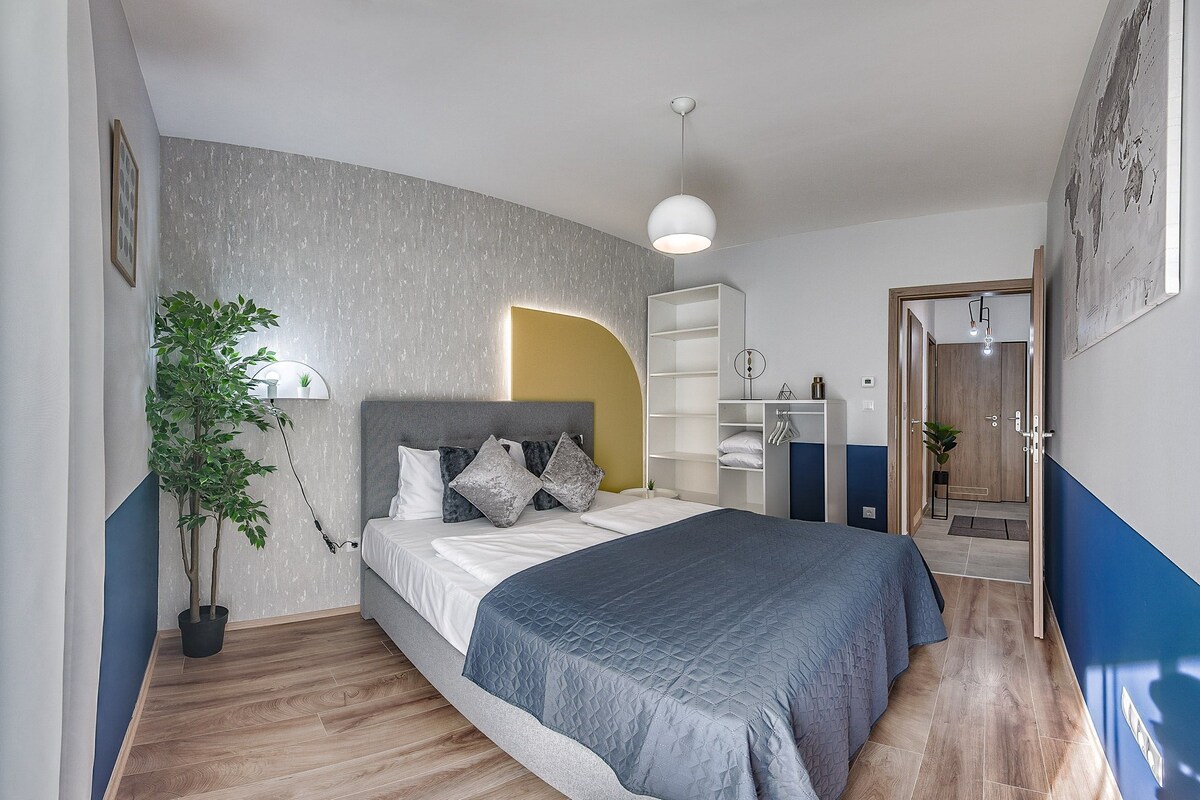 A modern bedroom with a bed, a potted plant, a wardrobe, and a world map on the wall.